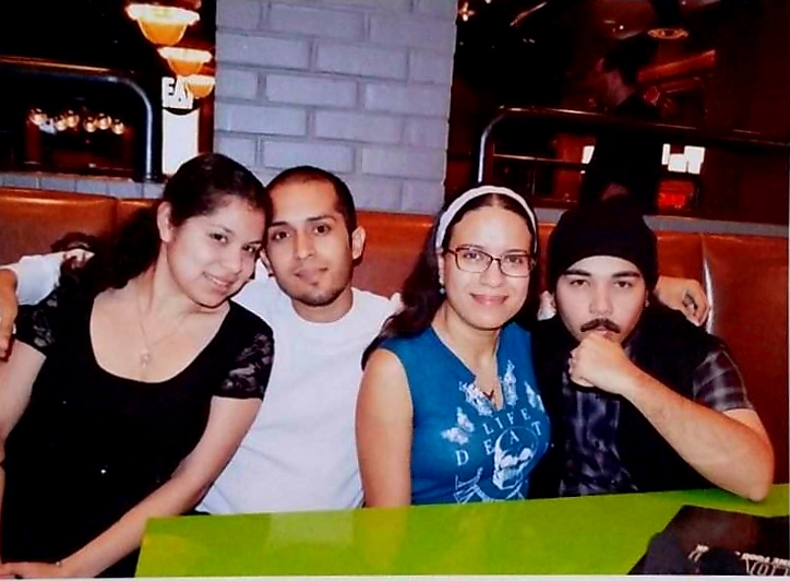 Two brunette couples, two boys and two girls, sit close together smiling.