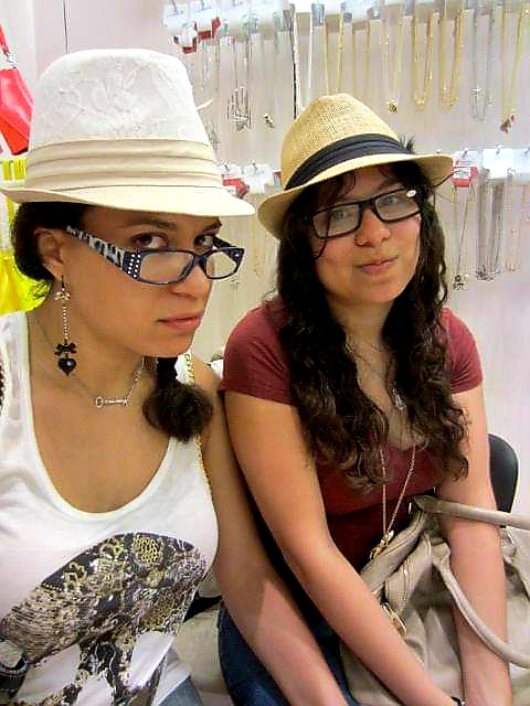 Two brunettes in fedoras make unamused faces at camera.