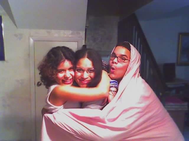 Three brunettes, two girls, one boy, embrace making silly faces.