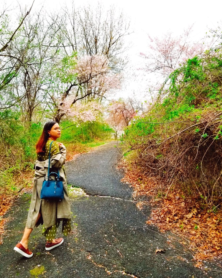 Brunette woman treads a paved florid path.