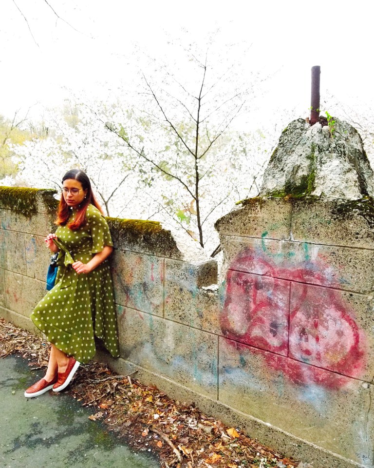 Brunette ties sash on olive green polka dot dress.
