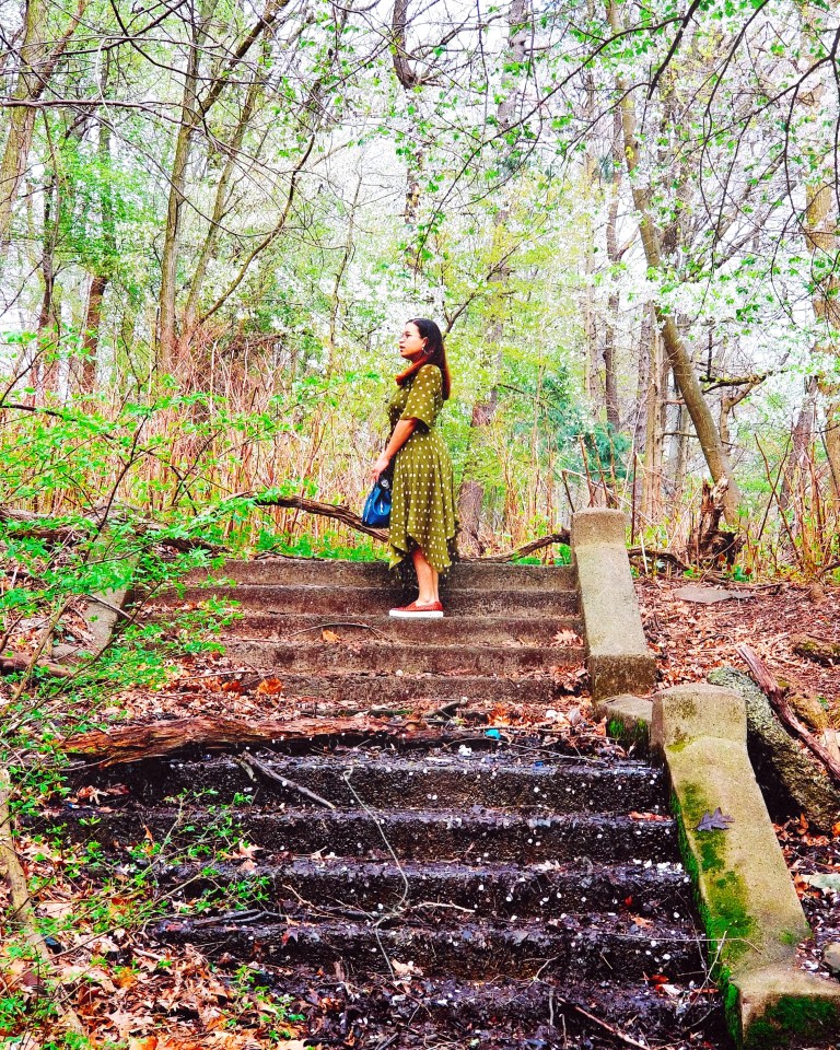 Brunette stands atop muddy stone stairs.